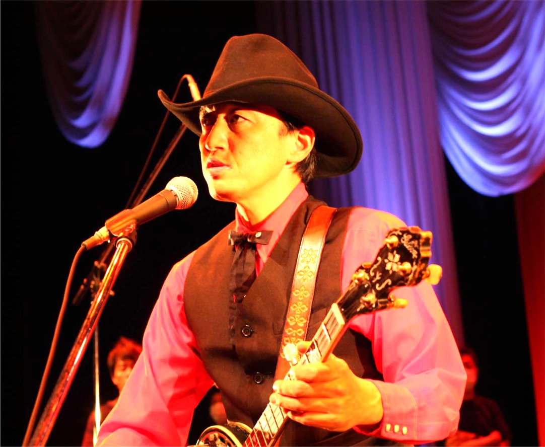 Satoshi Hara performing on stage with his banjo